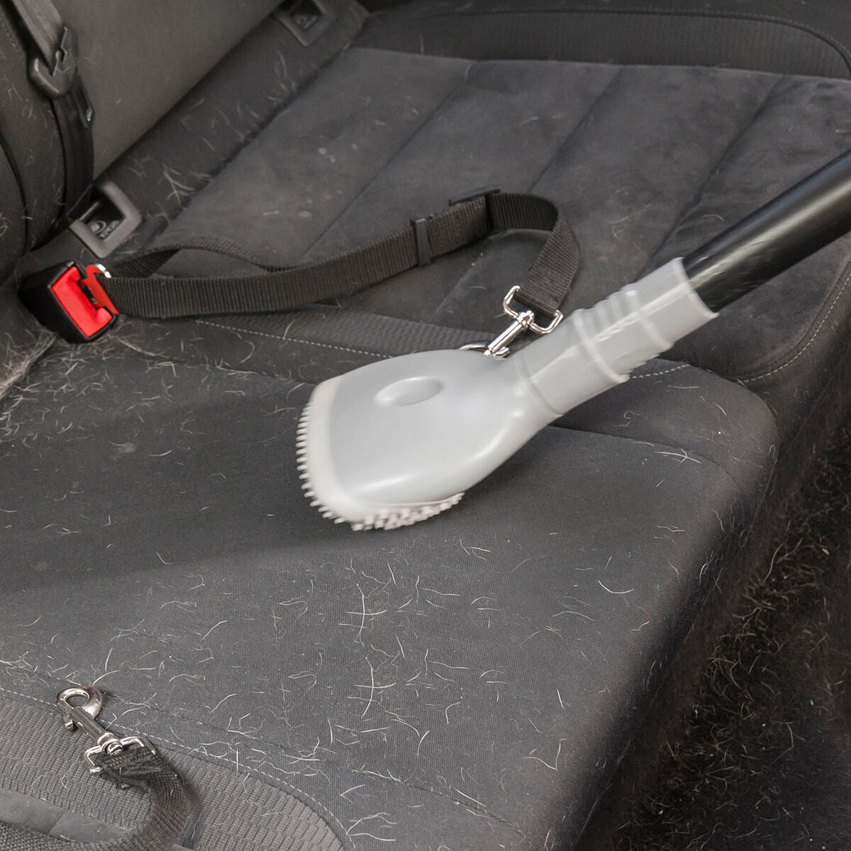 Utilisation de la brosse Smoovah pour retirer les poils d’un siège de voiture.